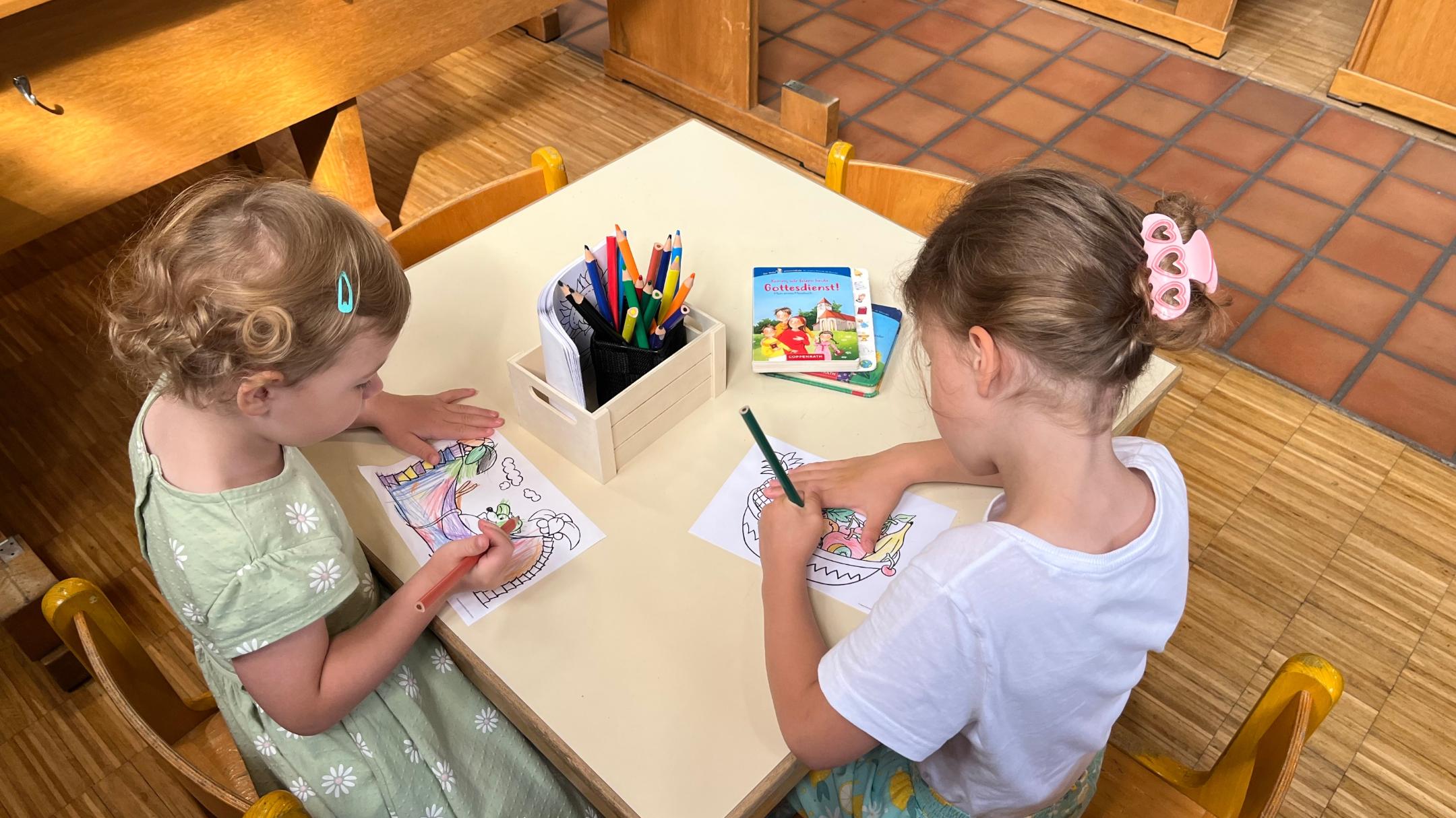 Zwei Kinder sitzen an einem Tisch und malen