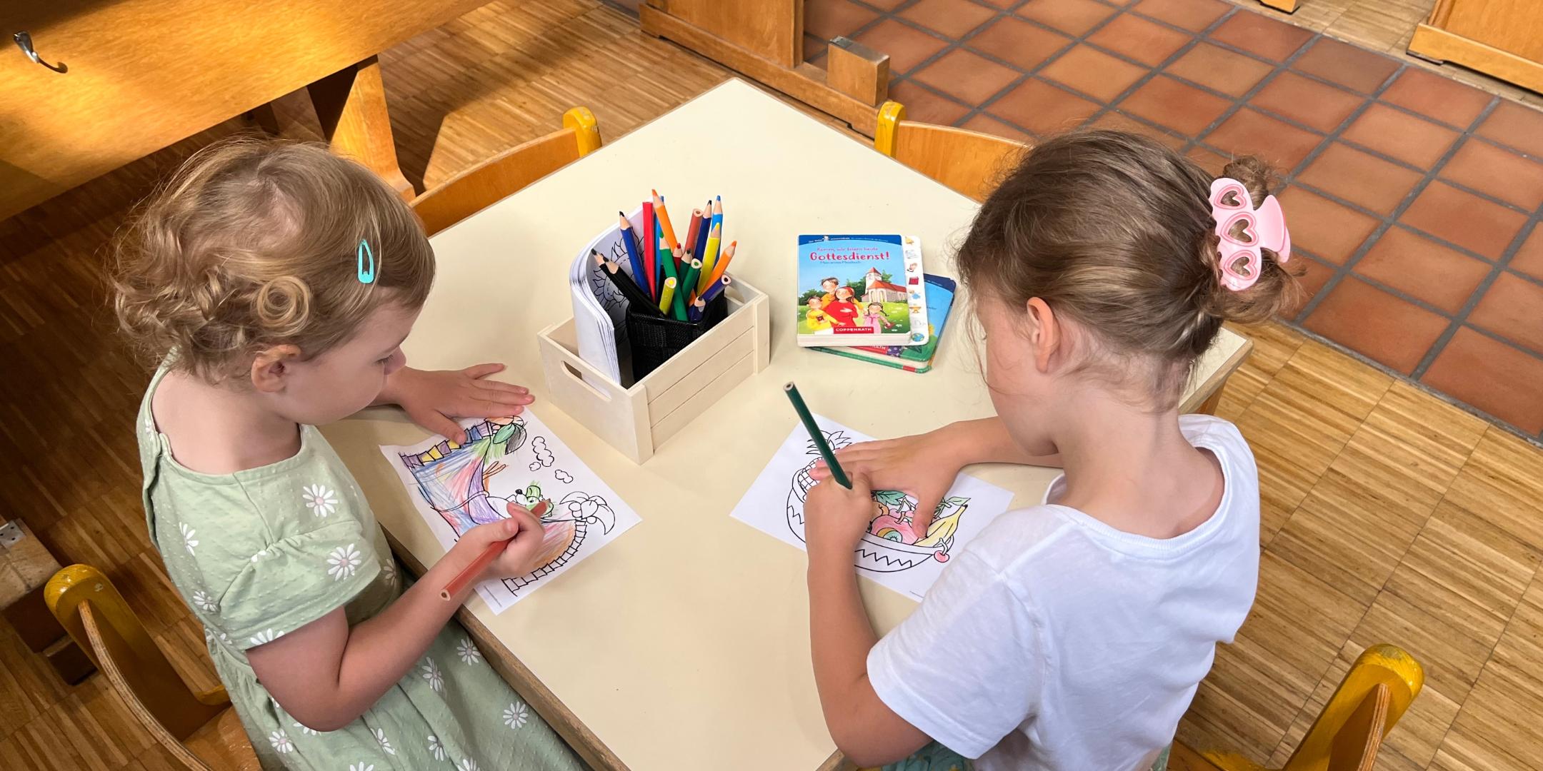 Zwei Kinder sitzen an einem Tisch und malen
