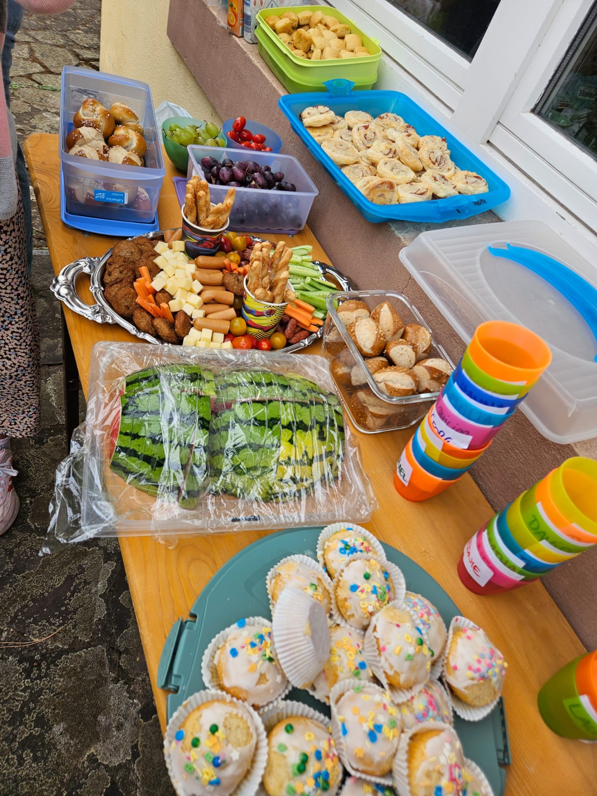 Tisch mit Muffins, Bechern, Gemüsesticks und anderem Fingerfood