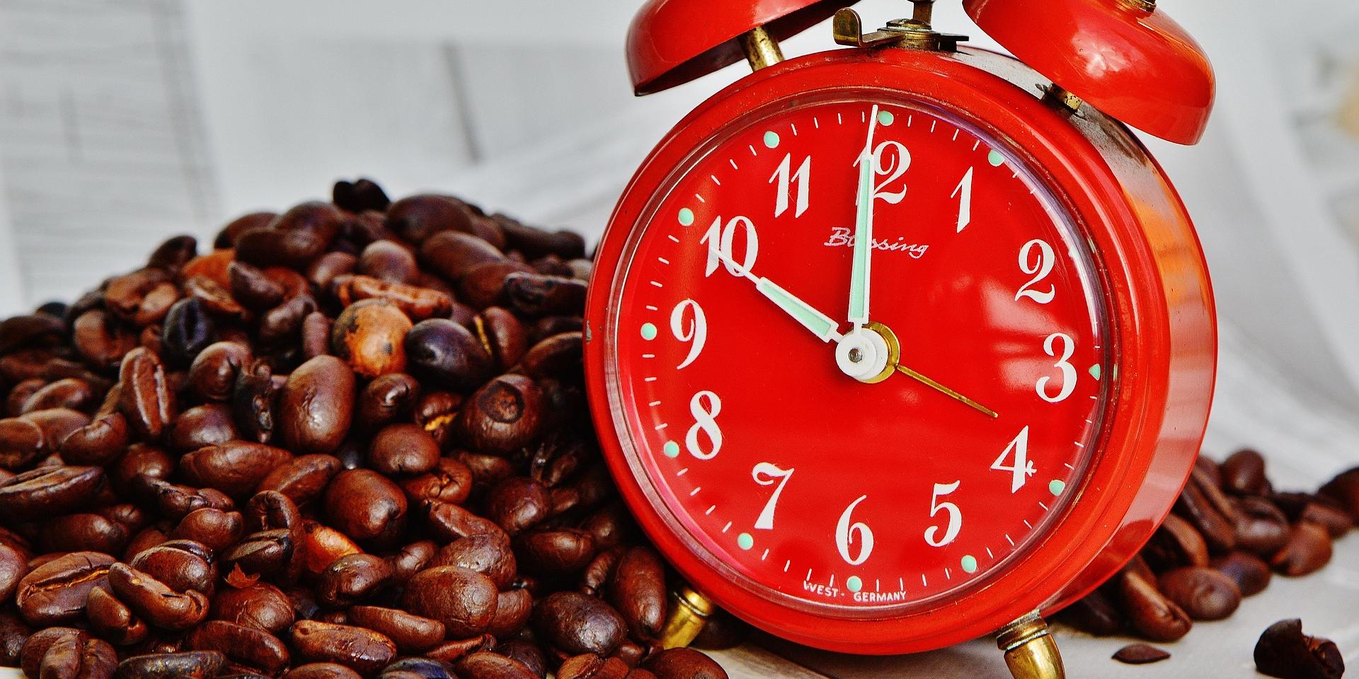 Roter Wecker neben einer Menge Kaffeebohnen